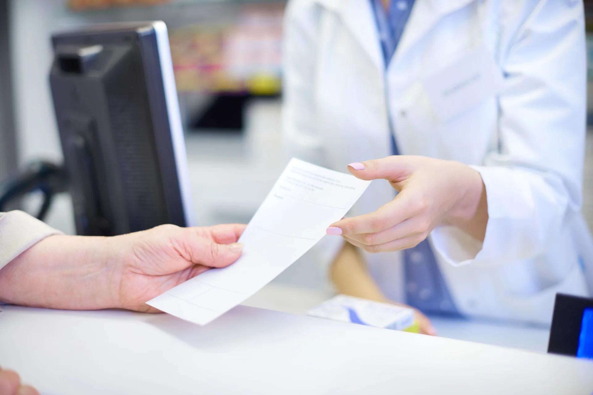 Farmacéutica entregando una receta a una clienta en una farmacia.